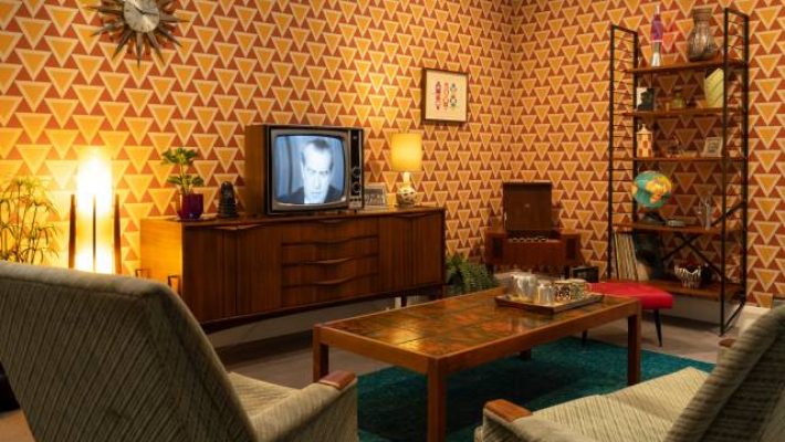 Cosy retro living room with vintage TV, patterned wallpaper, and mid-century furniture for a nostalgic vibe