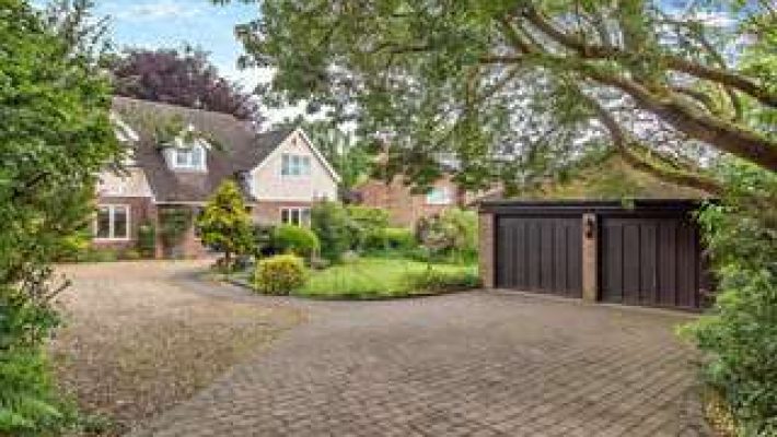 Charming English countryside home with lush garden and spacious driveway, featuring a classic pitched roof and garage