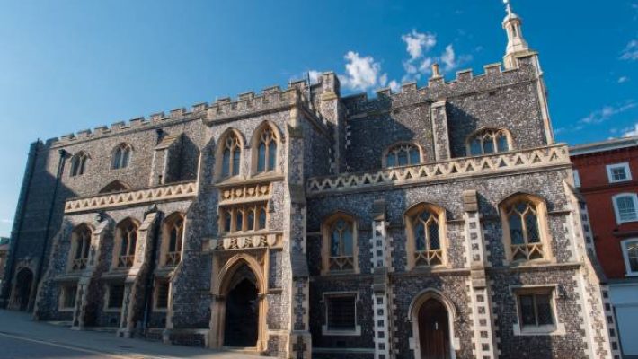 Historic gothic-style building with stone facade under a clear blue sky in the UK