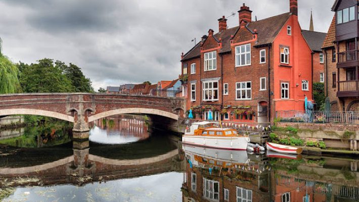 Charming red brick buildings by a tranquil river with a bridge in a picturesque UK townscape