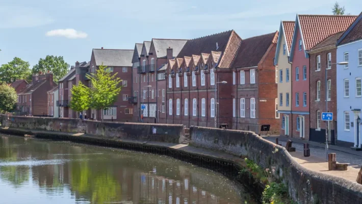 Charming riverside scene of colourful traditional houses and lush green trees along a tranquil waterway in the UK
