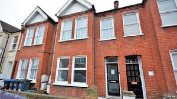 Red brick terraced house with bay windows and white trim in a residential UK neighbourhood