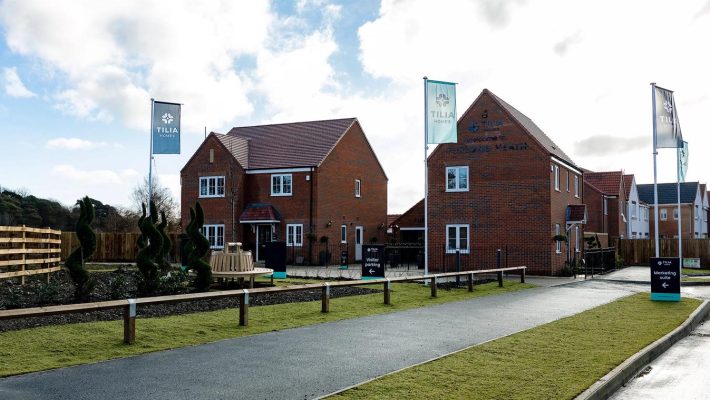 Modern English housing estate with brick homes, flags, and visitor parking at Tilia Homes development in the UK