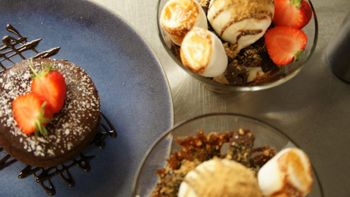 Delicious chocolate dessert with strawberries and bowls of ice cream topped with toasted marshmallows and crumbs