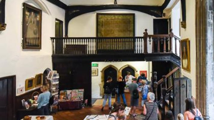Visitors exploring a historical building interior with exhibits and artwork in UK heritage site
