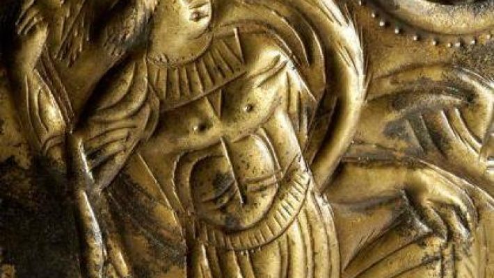 Ancient gold relief depicting a classical warrior with detailed armour and dynamic posture in a historical style