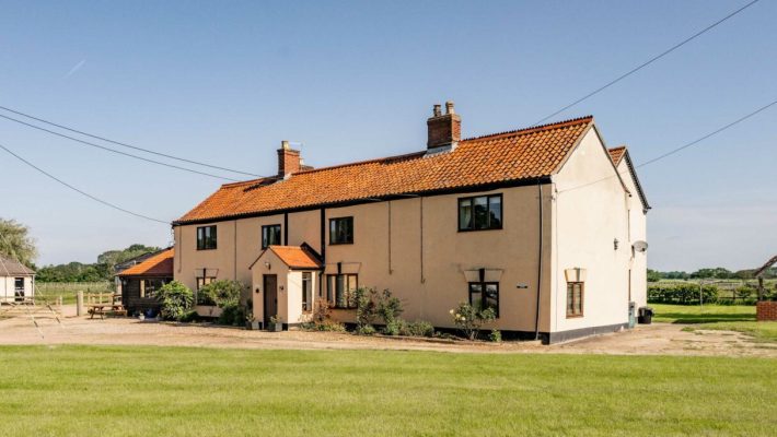 Traditional English countryside house with red-tiled roof and garden under clear blue sky