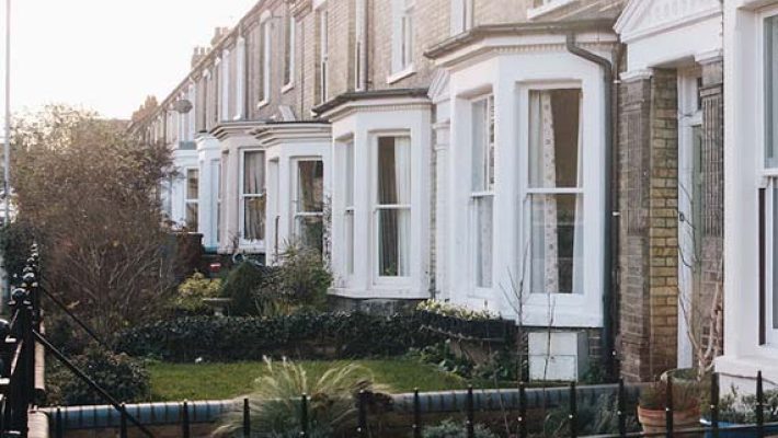 Row of traditional British terraced houses with gardens and sunset lighting