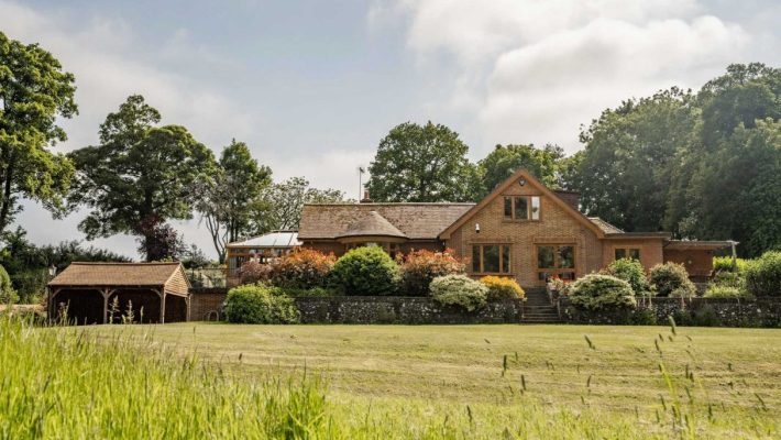 Charming country house in lush green landscape with trees and shrubs, brick architecture and serene countryside setting