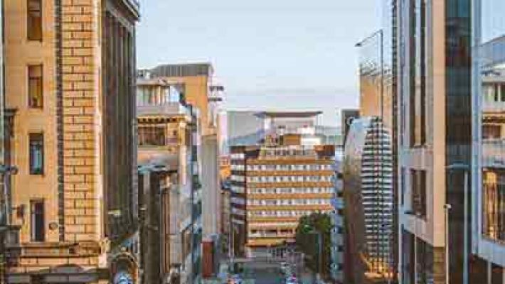 City street flanked by modern and historic buildings under a clear blue sky in the daytime urban setting