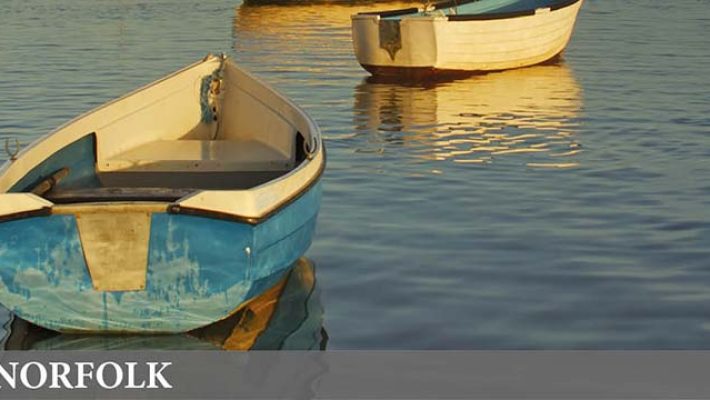 Two boats on a calm Norfolk waterway at sunset inviting visitors to explore the scenic beauty and tranquillity of the area