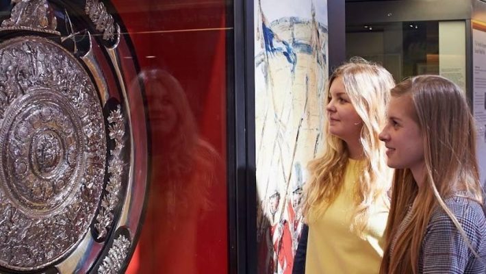 Visitors admire historical exhibits in a museum gallery showcasing artefacts and interactive displays