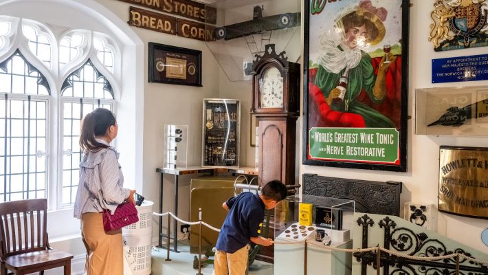 Visitors exploring historical museum exhibits with vintage signs and collectibles
