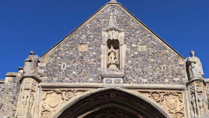 Close-up of a historic church facade with detailed stone carvings under a clear blue sky in the UK