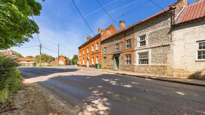 Street view of traditional English village with brick and stone buildings under a clear blue sky