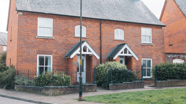 Red brick semi-detached houses with garden space in a residential UK street